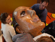 Two installation staff supporting the head of a giant puppet.