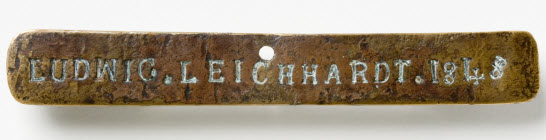 Close up of a metal strap with the words 'Ludwig Leichhardt 1848' engraved on the surface.